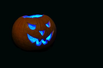 halloween pumpkin with ice blue eyes on black background