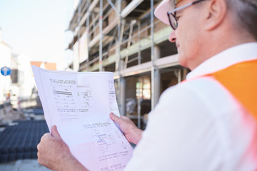 Bauarbeiter, Mann auf Baustelle mit Bauplan in der Hand