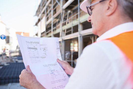 Bauarbeiter, Mann auf Baustelle mit Bauplan in der Hand