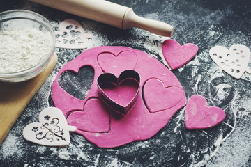 Baking concept for St. Valentines Day with heartshaped cutters and pink cookies on the dark table. Valentines day. Homemade  pink heart cookies. - 232941596