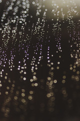 bokeh of lights made by raindrops on a windows illuminated by a torch, abstract background or texture shot