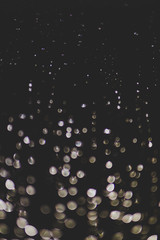 bokeh of lights made by raindrops on a windows illuminated by a torch, abstract background or texture shot