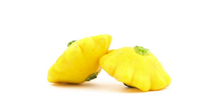 Two yellow patisson squashes. Rotating on the turntable. Isolated on the white background. Close-up. Macro.