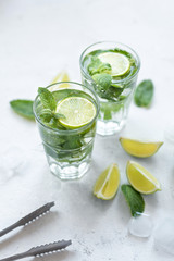 Summer refreshing cocktail mojito with lime and mint on white background.Slices of lime, mint, glass with ice cubes on white background.