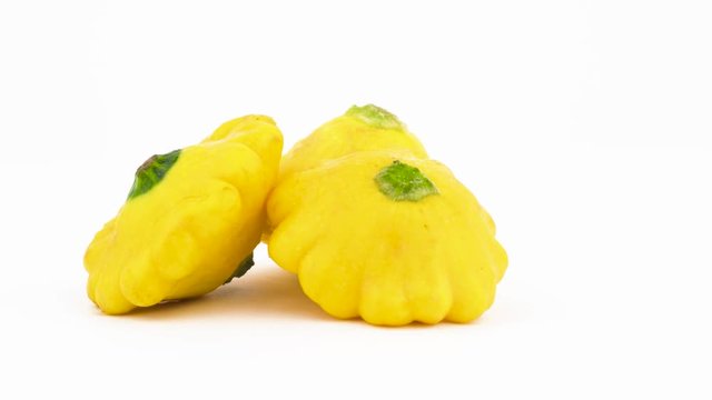 Two whole yellow pattypan squashes. Rotating on the turntable. Isolated on the white background. Close-up. Macro.