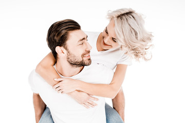 Handsome young adult man giving piggyback to wonderful blonde woman isolated on white