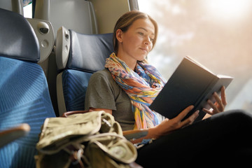 Relaxed young woman reading on the train - 232945707