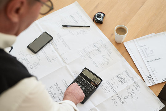 Schreibtisch von oben mit Taschenrechner, Plan, Mann