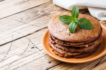 Chocolate pancakes with berry jam and mint for Breakfast on wooden background