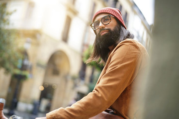 Hipster guy standing with bicycle in the street