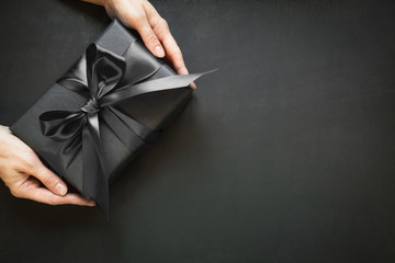 Black gift box in female hand. Top view. Black friday. Shopping and sales.