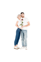 Attractive young adult couple with flower hugging while looking at camera isolated on white