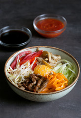Traditional Asian Bibimbap dish with rice and vegetables on dark background