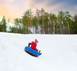 winter, leisure and entertainment concept - happy teenage girl sliding down hill on snow tube