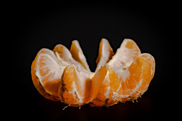 Half peeled mandarin on a black background close-up