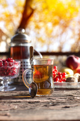 Autumn still life with tea cup on wooden planks and blur trees on background.