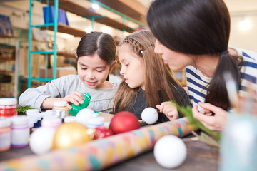 Portrait of two little kids making Christmas decorations in crafting class with smiling female teacher