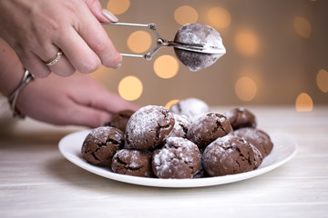 Sprinkling powdered sugar on chocolate cookies crinkles