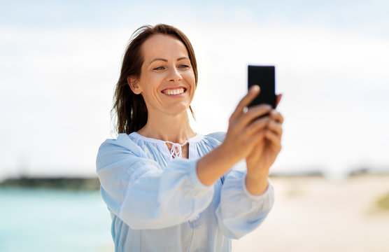summer holidays and leisure concept - happy smiling woman taking selfie on beach