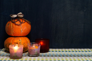 Decorative pumpkins and burning candles on black