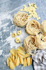 Mixed types and shapes of italian pasta on grey stone, background