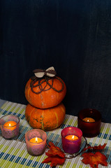 Orange pumpkins and burning candles on black