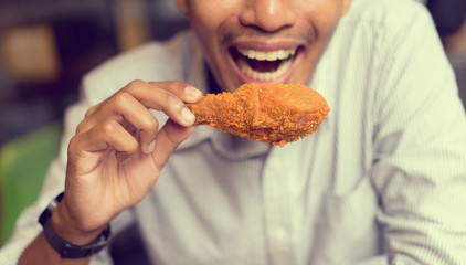 close up focus man hold leg of fried chicken meal for eat at restaurant bar,fast food...