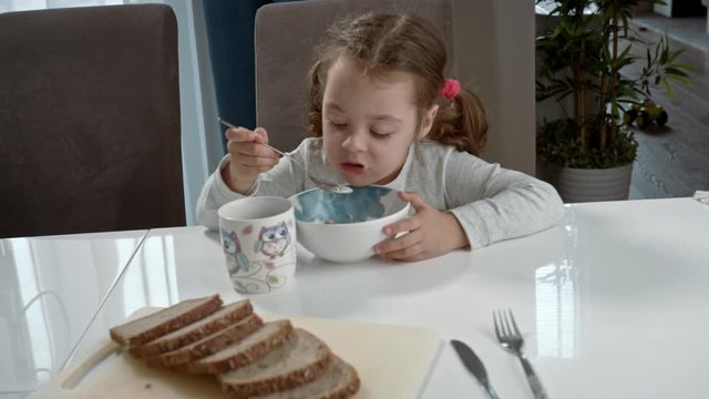 Cute, little girl eating flakes with milk