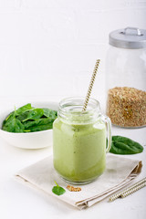 Green smoothie drink in glass jar on white. Mixed cocktail with spinach and green buckwheat.