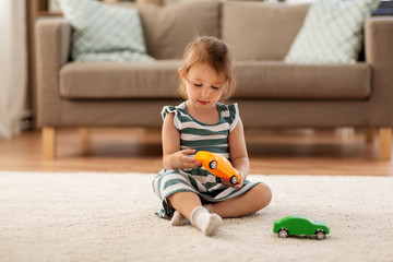 childhood and people concept - happy three years old baby girl playing with toy car at home