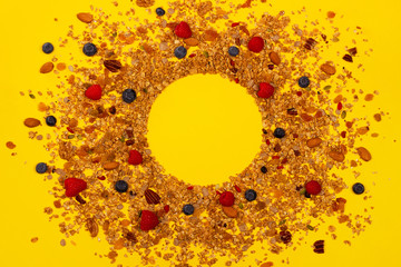 Creative background from scattered granola, nuts and berries on yellow. Healthy eating concept. Top view. Flat lay. Place for your text.