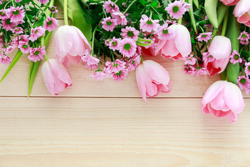 Pink tulips and chrysanthemums on wooden background