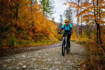 Fototapeta na wymiar Cycling woman riding on bike in autumn mountains forest landscape. Woman cycling MTB flow trail track. Outdoor sport activity.