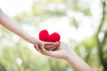 Fototapeta na wymiar Hand giving red heart to hand. Love , health care , health insurrance concept.