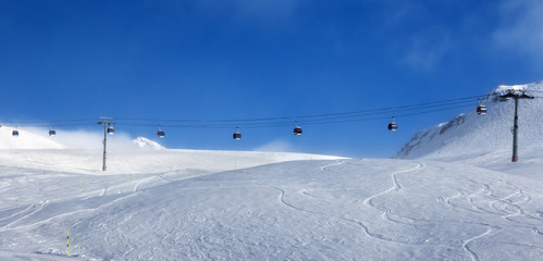 Panoramic view on gondola lift and off-piste ski slope in fog