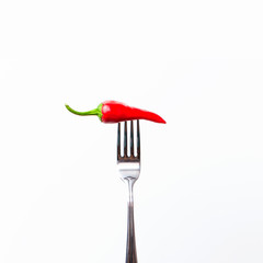 Fototapeta na wymiar Red bitter chili pepper on the fork on white isolated background. Creative Food concept.