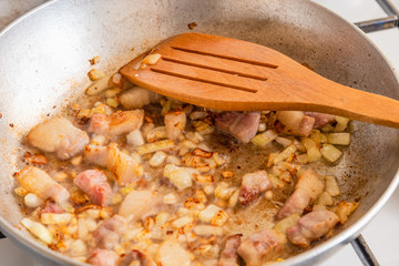 Bacon and onion fried in a pan closeup