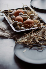 Raw quail, chicken eggs on black plate, easter concept, dark concrete background, top view, 