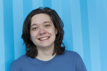 Portrait of Young man with long hair looking at camera. Teenage.