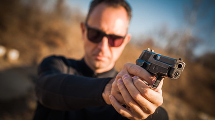 Police agent bodyguard gun pointing pistol to attacker. Front view