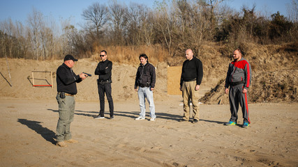 Shooting range instructor demonstrate gun shoot techniques to his students