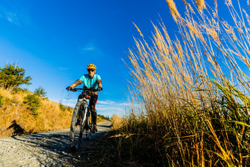 Fototapeta premium Cycling woman riding on bike in autumn mountains forest landscape. Woman cycling MTB flow trail track. Outdoor sport activity.