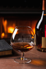 glass of cognac in front of fireplace