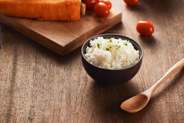 Grains of rice in a wooden bowl and ingredients for a vegetarian recipe - healthy eating concept