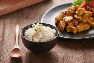 White rice with curry and chicken in black plate on wooden table