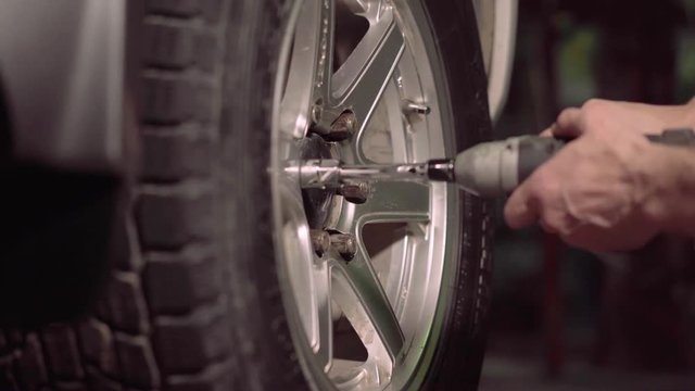 Tighten car tire nuts. Man using an impact wrench for tighten the nuts of car tire.4k,30fps.