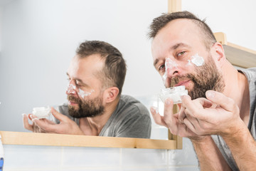Man applying moisturizer cream in bathroom