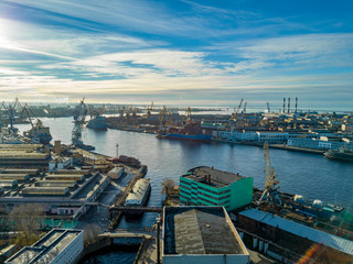 Aerial; drone view of port with shipyard silhouettes on the horizon; industrial cityscape in sunny weather with blue sky; process of ship repairing, logistic import export and transport background