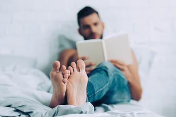 Obraz premium selective focus of man reading book in bedroom at home