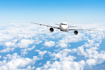 Airplane jet flying at flight level high in the sky above the clouds and blue sky. © aapsky